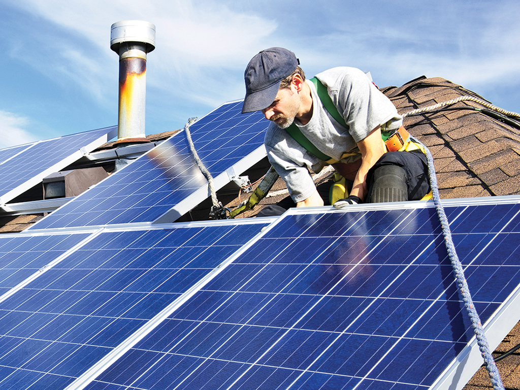 Man installing alternative energy photovoltaic solar panels on roof